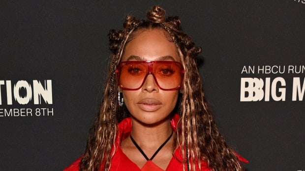 La La Anthony poses in a series of high buns, a bright red coat and red-tinted sunglasses.