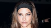 Barbara Palvin wears a black headband in her long brown hair and poses for the camera.