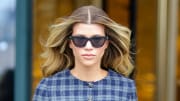 Sofia Richie wears black sunglasses and a navy plaid dress as she walks the streets of Paris.