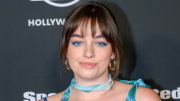 Sixtine smiles at the camera wearing a blue floral dress and neck-tie and her brown hair in an updo.