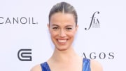 Hailey Clauson poses in a blue shimmery dress and a slicked-back hairdo and smiles for the camera.
