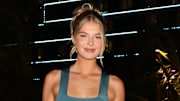 Ellie Thumann poses in a teal dress and wears her blonde hair in an up-do.