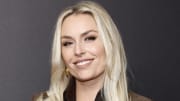 Lindsey Vonn poses in a black top and brown suede blazer and smiles for the camera.