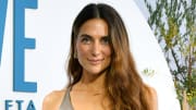 Melissa Wood-Tepperberg poses in a metallic sports bra and wears her wavy brown hair down.