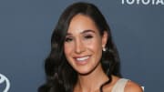 Kayla Itsines sports her black hair in a Hollywood wave and smiles for the camera.
