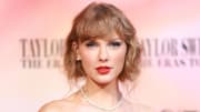 Taylor Swift sports a red lip and her waves in a messy up-do and poses for the camera.