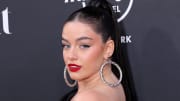 Sixtine sports a red lip and oversized silver hoops and looks over her shoulder at the camera.