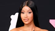 Cardi B poses in a silky down-do and full eyelashes and smiles softly for the camera.