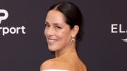 Ana Ivanovic poses in a white off-the-shoulder gown and smiles over her shoulder at the camera.