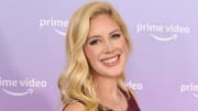 Heidi Montag poses in a deep red dress and a soft wave and smiles at the camera.