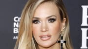 Carrie Underwood sports oversized black diamond cross earrings and poses for the cameras.
