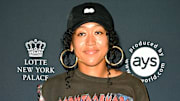 Naomi Osaka poses in a graphic tee, black ball cap and oversized hoops and smiles for the camera.