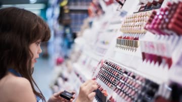 Girl looking at make-up display on a shelf in a shop.