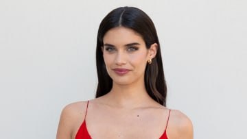 Sara Sampaio poses in front of a white backdrop in a red spaghetti strap slip dress.