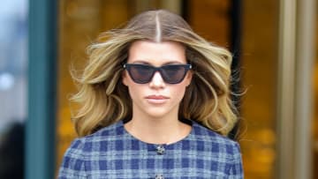 Sofia Richie wears black sunglasses and a navy plaid dress as she walks the streets of Paris.