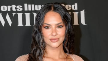 Christen Harper poses in a light pinky sparkly dress and a soft wave in her black hair.