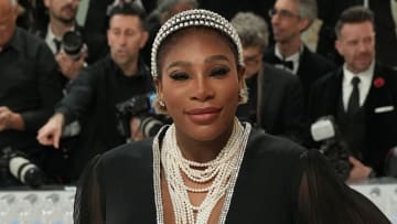 Serena Williams poses in a floor-length black gown, pearl necklaces and a pearl headband.