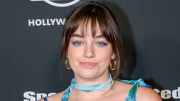 Sixtine smiles at the camera wearing a blue floral dress and neck-tie and her brown hair in an updo.