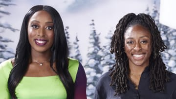 Chiney Ogwumike poses in a green dress and pink lipstick and smiles at the camera beside her sister, Nneka, who wears a black button-down.