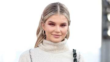 Ellie Thumann smiles in a cream-colored turtleneck and wears her dirty blonde hair pinned back.