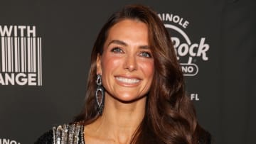 Melissa Wood-Tepperberg poses and smiles wearing a black and silver sparkly dress and matching dangle earrings.