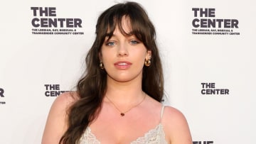 Sixtine wears a cream lace-trimmed dress and her hair in a soft wave.