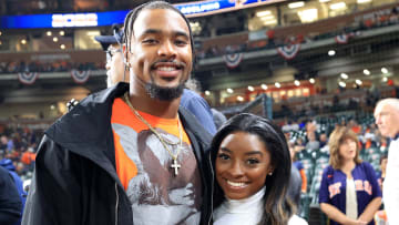 Jonathan Owens and Simone Biles pose side-by-side at a Houston Astros game and smile for the camera.