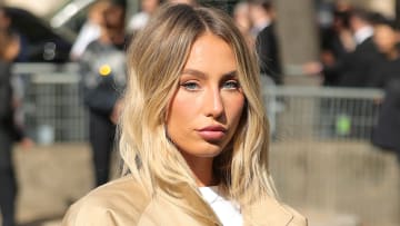 Alix Earle poses in a white tee and a tan bomber jacket.