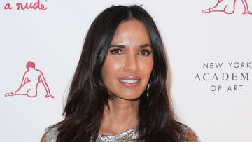 Padma Lakshmi poses in a silver metallic top and a glossy lip.