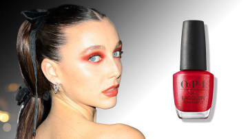 On the left, Emma Chamberlain sports red eye makeup and a slicked-back up-do and looks over her shoulder at the camera. On the left, there is a bottle of red OPI nail polish.