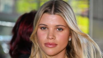 Sofia Richie poses with her dirty blonde hair in a blow out and looks at the camera.