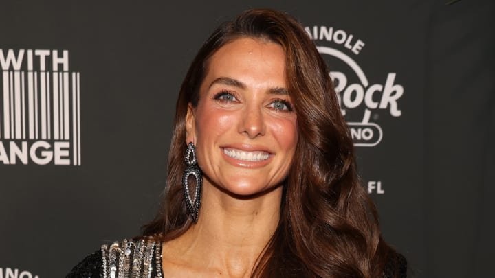 Melissa Wood-Tepperberg poses and smiles wearing a black and silver sparkly dress and matching dangle earrings.