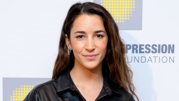 Aly Raisman poses in a black leather top and silver chain earrings and smiles softly for the camera. Aly Raisman poses in a black leather top and silver chain earrings and smiles softly for the camera.