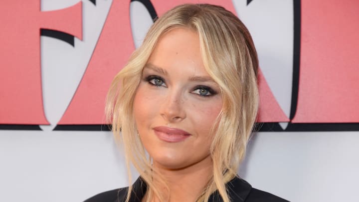 Camille Kostek poses in a black blazer and edgy black eye makeup.