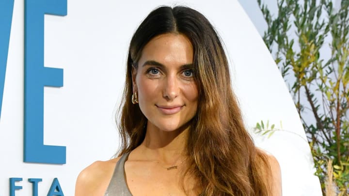 Melissa Wood-Tepperberg poses in a metallic sports bra and wears her wavy brown hair down.
