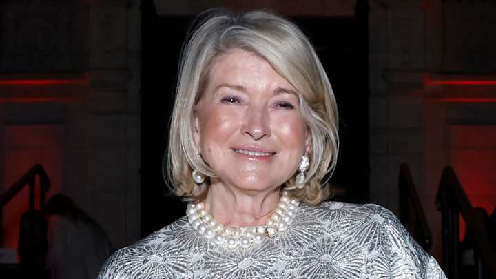 Martha Stewart poses in a silver floral top and strings of pearls and smiles for the camera.