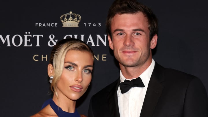 Paige Lorenze and Tommy Paul pose side-by-side on the red carpet and smile for the camera.