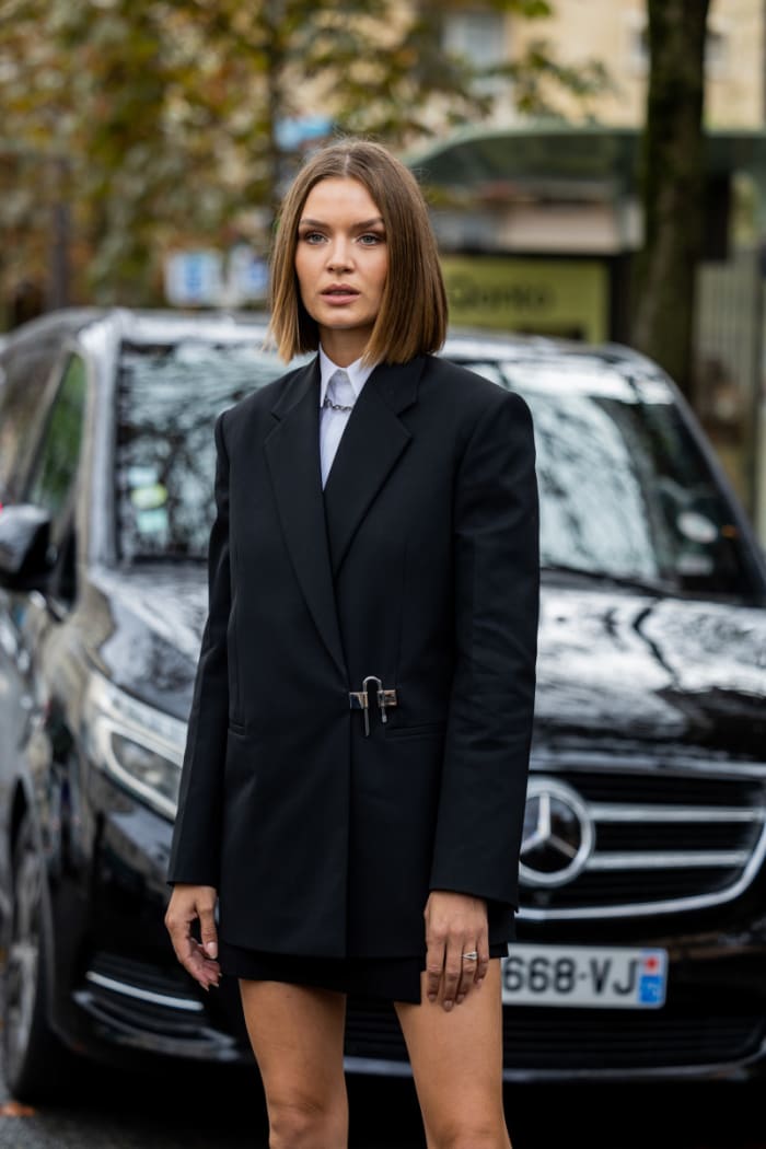 Josephine Skriver wears black blazer, boots, white button shirt on day seven of Paris Fashion Week.