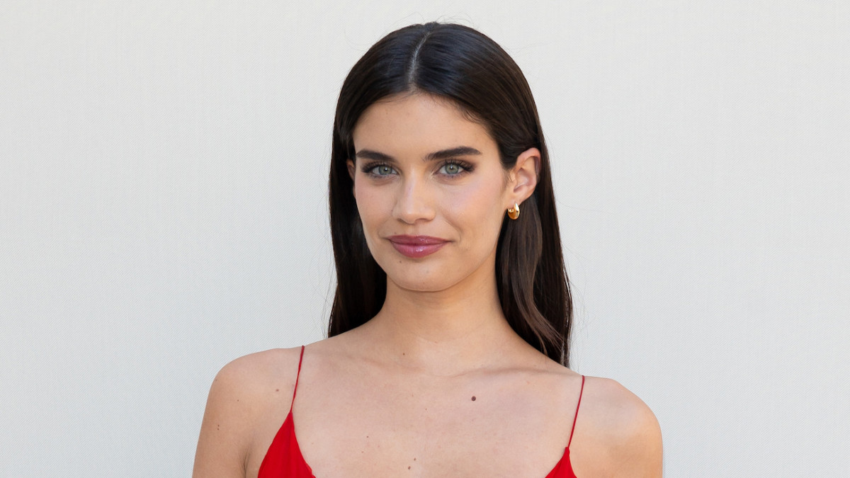 Sara Sampaio poses in front of a white backdrop in a red spaghetti strap slip dress.