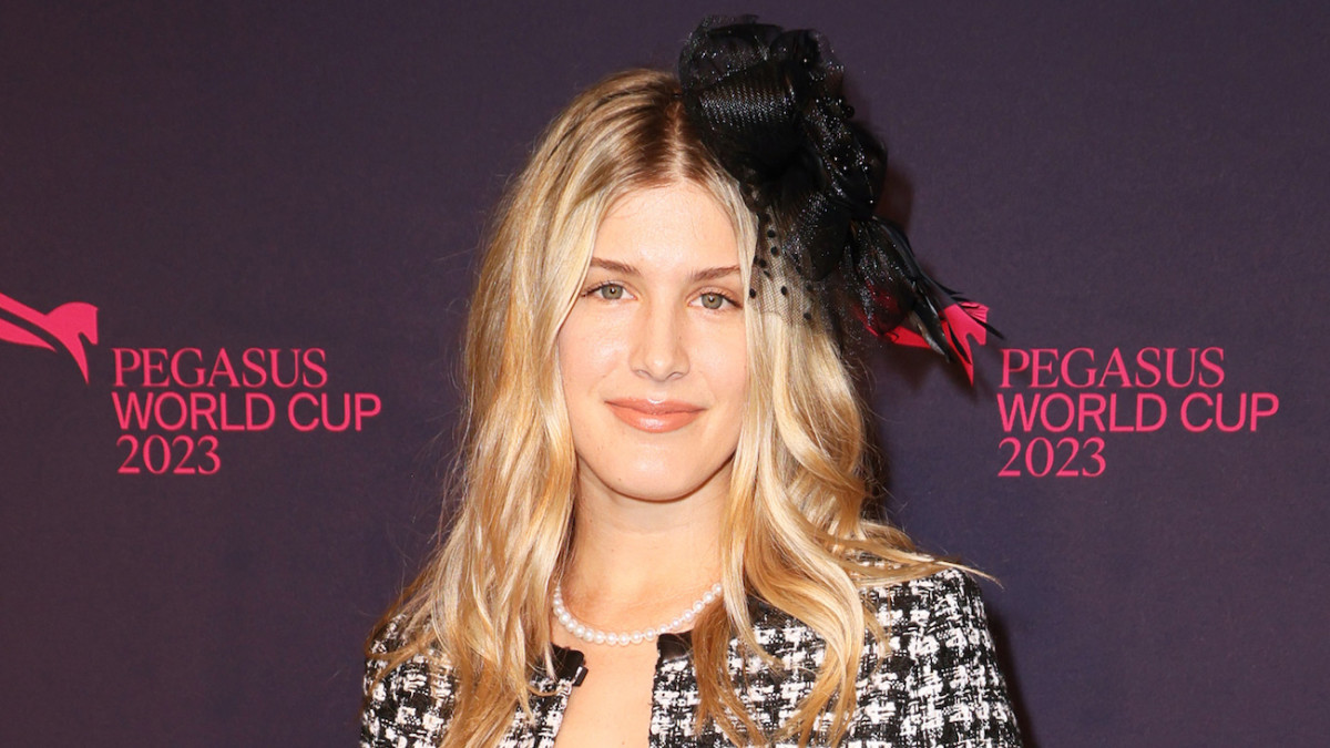 Genie Bouchard poses in a black and white tweed blazer and a black floral hair piece.