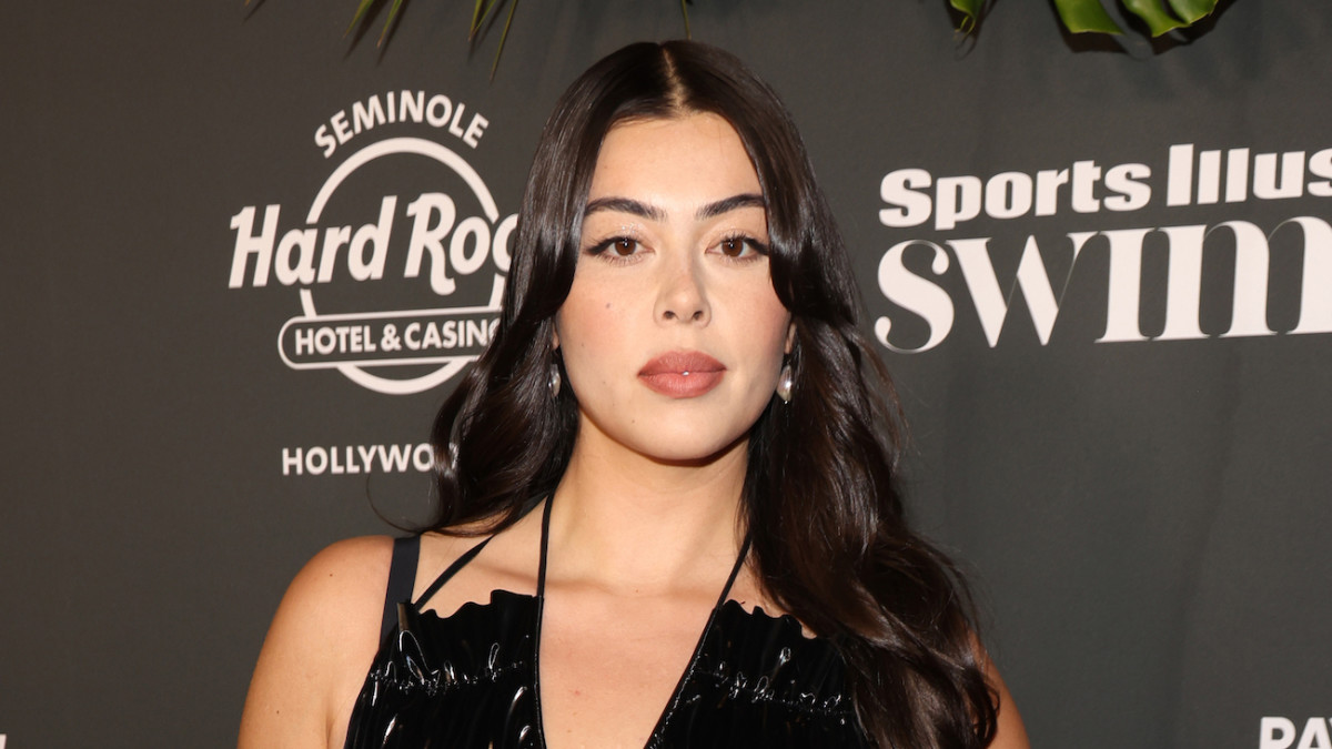 Lauren Chan poses in a black halter neck dress in front of a black backdrop.