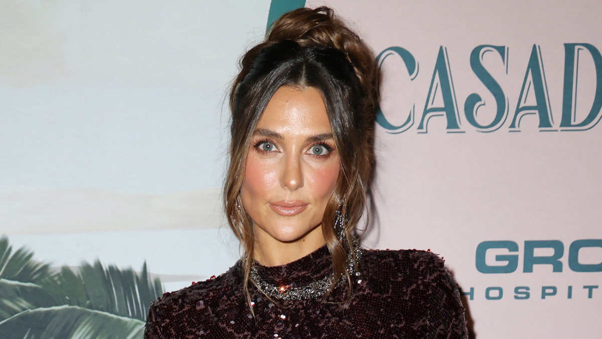 Melissa Wood-Tepperberg poses in a dark plum sequined dress and wears her brown hair in messy up-do.