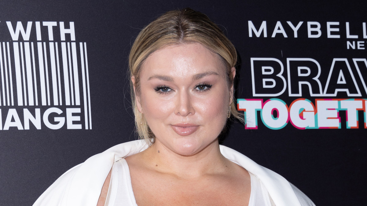 Hunter McGrady smiles for the camera wearing a white top and a minimal face of glam.