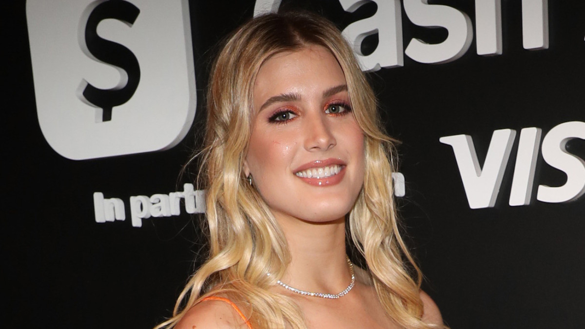 Genie Bouchard smiles for the camera wearing a diamond necklace and sporting a full lash and glossy lip.