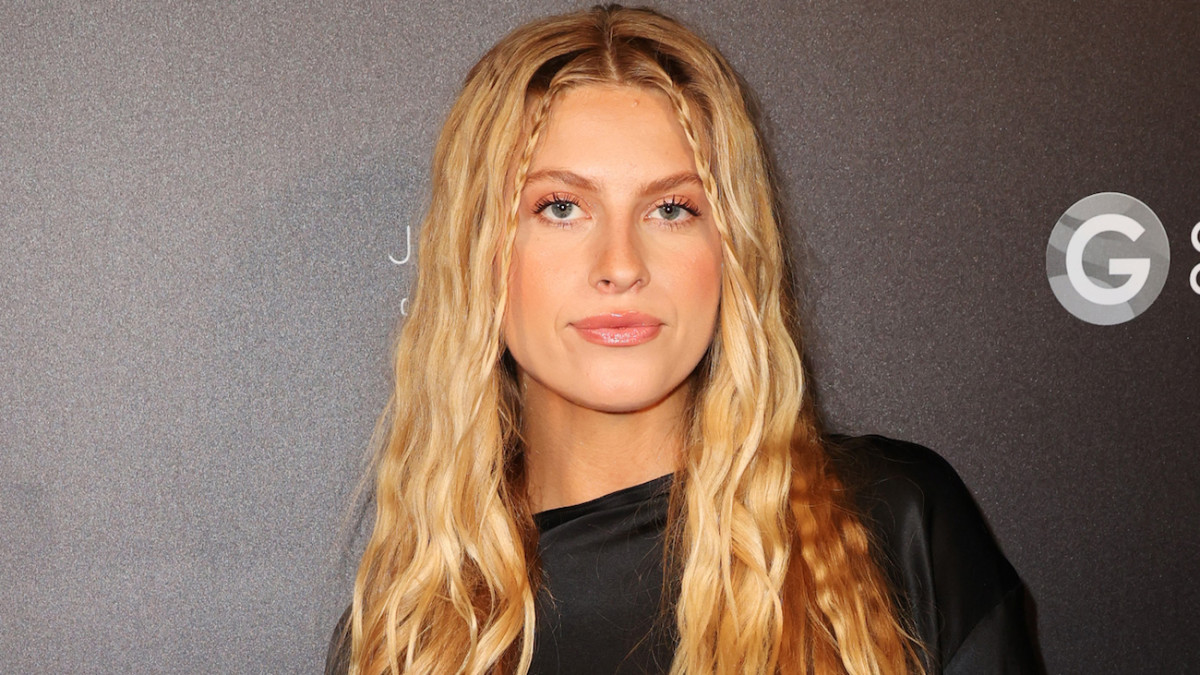 Xandra Pohl poses for the camera in a black silk top and braided blonde hair.