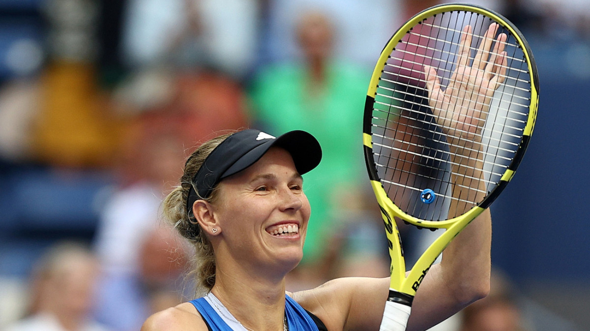 Caroline Wozniacki smiles and claps her racket after winning a match.