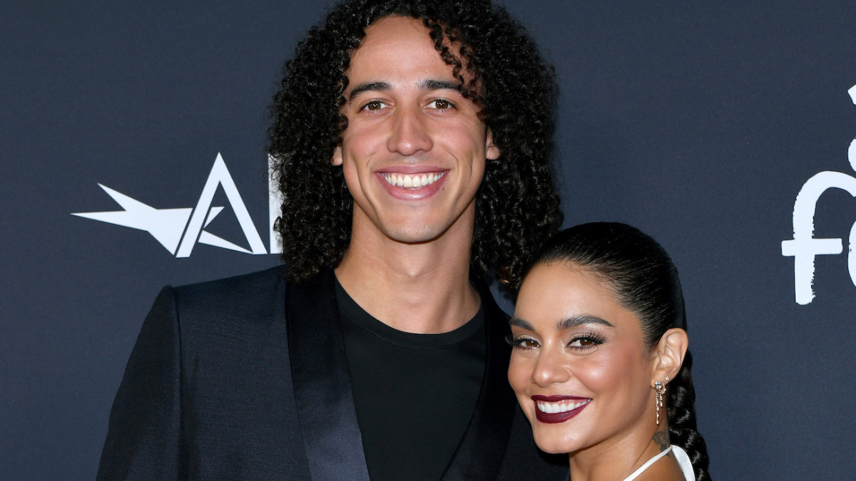Cole Tucker and Vanessa Hudgens pose together on the red carpet and smile for the camera.