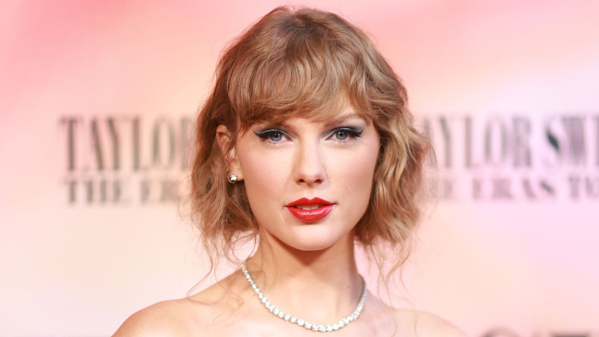 Taylor Swift sports a red lip and her waves in a messy up-do and poses for the camera.