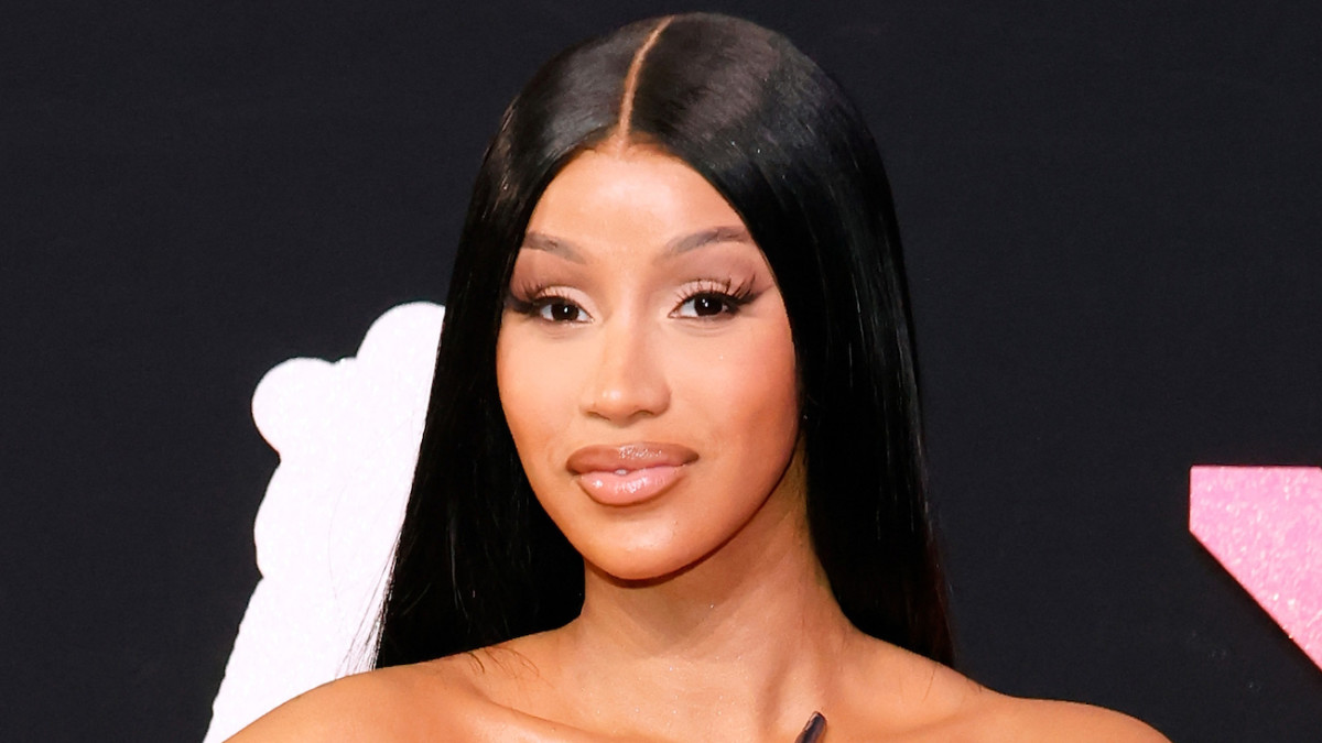 Cardi B poses in a silky down-do and full eyelashes and smiles softly for the camera.