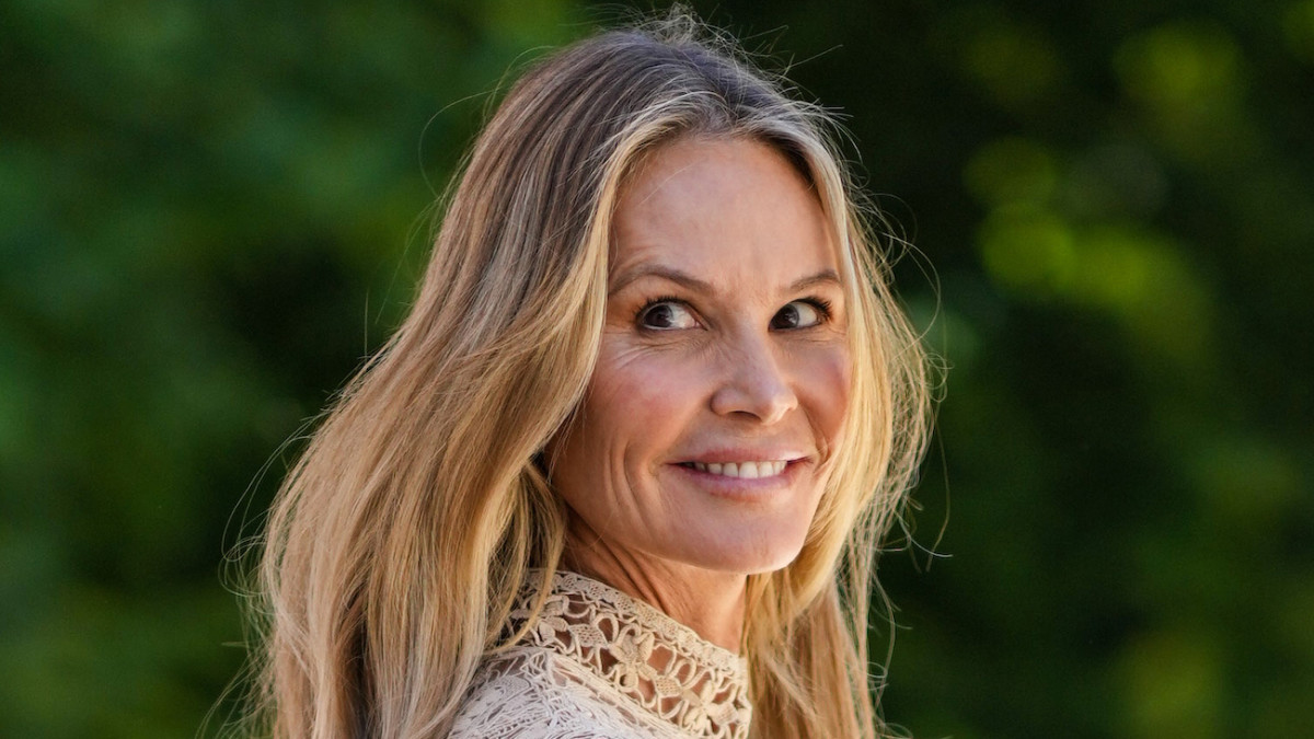 Elle Macpherson wears a high-neck knit dress and smiles over her shoulder at the camera.